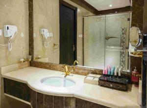 uma casa de banho com um lavatório e um espelho grande em Rest Night Hotel Apartment- AlHamra em Riade
