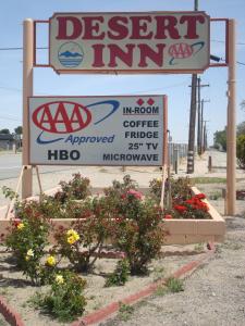 um sinal para uma estalagem de sobremesas com algumas flores em Desert Inn em Mojave