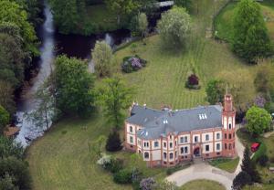 Vue aérienne d'une maison sur une colline avec une rivière dans l'établissement Hotel Schloss Gamehl, à Wismar