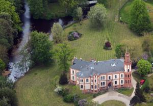 eine Luftansicht eines Hauses auf einem Hügel mit einem Fluss in der Unterkunft Hotel Schloss Gamehl in Wismar