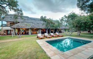 a resort with a pool and chairs and a building at Tintswalo Safari in Manyeleti Game Reserve
