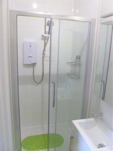 a shower with a glass door next to a sink at Chalice Lodge in Glastonbury