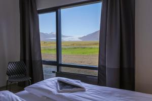 a bed sitting in front of a window with a view of the ocean at Lilja Guesthouse in Höfn