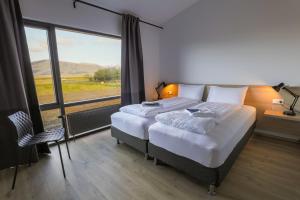 a bedroom with two beds and a large window at Lilja Guesthouse in Höfn