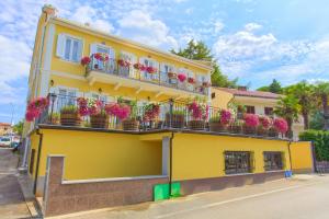 żółty budynek z skrzyniami kwiatowymi na balkonach w obiekcie Frajona Apartments w mieście Malinska