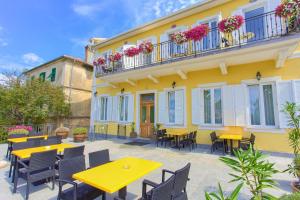 a patio with yellow tables and chairs and a yellow building at Frajona Apartments in Malinska