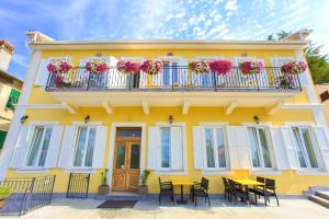 a yellow house with tables and chairs in front of it at Frajona Apartments in Malinska