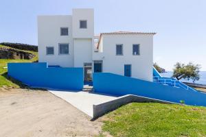 a white house with a blue fence in front of it at Lofts Azul Pastel in Horta