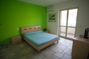 レッジョ・ディ・カラブリアにあるB&B dormirereggiocalabriaの緑のベッドルーム(ベッド1台、窓付)