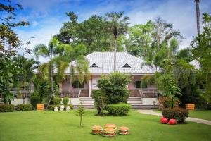 una casa rosa con un patio verde con flores rojas en Watermill Resort, en Nong Nam Daeng