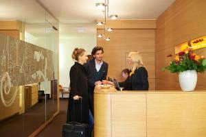 un groupe de personnes debout à un bureau de réception dans l'établissement Hotel VICTORIA Nürnberg, à Nuremberg