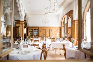 een restaurant met witte tafels en stoelen en een kroonluchter bij Meisser Hotel "superior" in Guarda