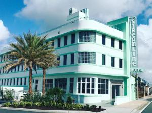 un bâtiment bleu avec un palmier devant lui dans l'établissement The Streamline Hotel - Daytona Beach, à Daytona Beach