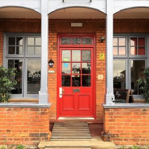 una puerta roja en un edificio de ladrillo con ventanas en Blyth Hotel, en Southwold