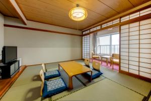 Zimmer mit einem Tisch, Stühlen und einem TV in der Unterkunft Kyukamura Ibusuki in Ibusuki