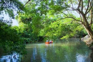 twee mensen zitten in een boot op een rivier bij Watermill Resort in Nong Nam Daeng
