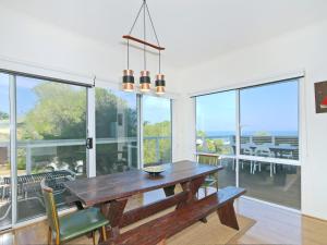 a dining room with a wooden table and large windows at Kiltevna - Maslin Beach - C21 SouthCoast Holidays in Maslin Beach