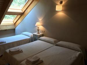 2 Betten in einem Zimmer mit 2 Fenstern in der Unterkunft Ático Balcon De Jaca II in Jaca