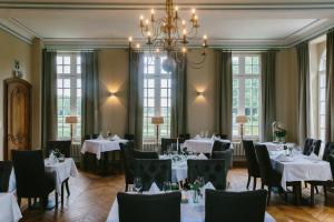 a dining room with tables and chairs and a chandelier at Kasteel Pietersheim Maastricht - Lanaken in Lanaken