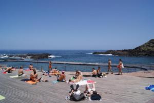 a group of people sitting on a pier near the water at Apartamento Mesa del Mar in Puerto de la Madera