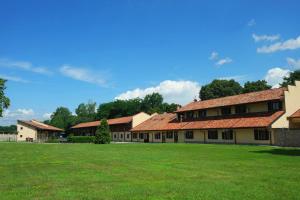 szereg budynków z czerwonymi dachami na zielonym polu w obiekcie Country Hotel Castelbarco w mieście Vaprio dʼAdda