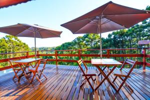 two tables and chairs with umbrellas on a deck at Pousada Ágape in Monte Verde