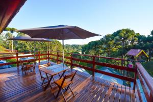 a deck with tables and chairs and an umbrella at Pousada Ágape in Monte Verde