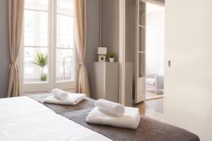 バルセロナにあるEnjoy Apartments Borrellの白いベッドルーム(ベッドにタオル2枚付)