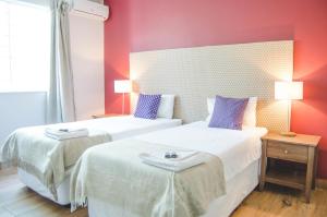 2 Betten in einem Zimmer mit roten Wänden in der Unterkunft Hokahanya Inn & Conference Centre in Maseru
