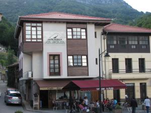 un gran edificio con gente sentada fuera de él en Hotel Rural la Plaza en Caso