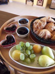 a table with a plate of bread and grapes and croissants at B&B La Rosa Dei Venti in Donnalucata