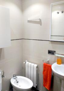een badkamer met een wastafel, een toilet en een spiegel bij Cangas Plaza in Cangas de Onís