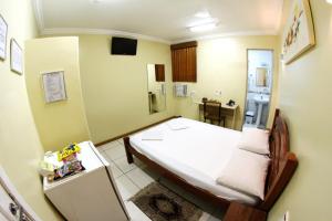 a small bedroom with a bed and a refrigerator at Hotel Belem Fortaleza in Fortaleza