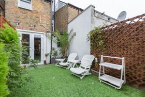 eine Terrasse mit Stühlen, einem Tisch und einem Zaun in der Unterkunft Watford General Suites in Watford