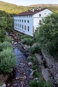 a white building next to a river in front of a river at Hotel Valle del Jerte in Jerte