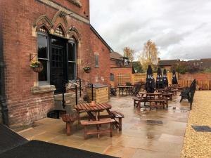 a patio with wooden tables and benches on a brick building at The Godwins in Hereford