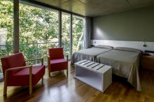 a bedroom with a bed and two chairs and a large window at Hotel Valle del Jerte in Jerte +31 photos