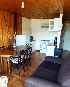 a living room with a table and a kitchen at Cabañas Rupu Lafquén in Pichilemu