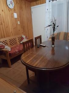 a dining room with a wooden table and a couch at Cabañas Rupu Lafquén in Pichilemu +4 photos