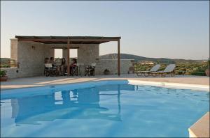 a swimming pool with people sitting at a table at Liostasi Country Houses in Palekastron