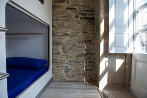 Habitación con sofá azul y pared de piedra. en Hostel Cross en Lugo