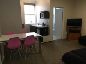een kamer met een tafel en vier roze stoelen bij Motel on Carroll in Dunedin