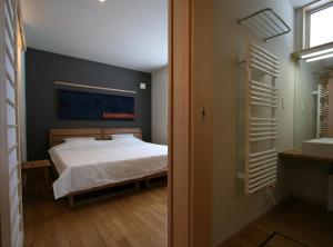 a bedroom with a bed and a bathroom with a sink at Forest View in Furano