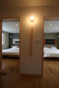a room with two beds and a door with a mirror at Forest View in Furano
