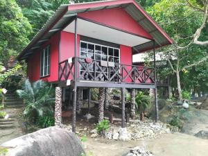 a small red and white house with a balcony at Simukut Place in Kampong Pasir Sanang Burong