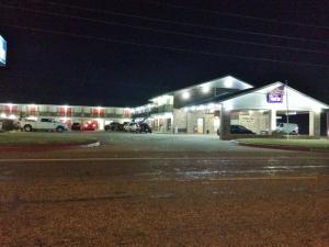 een tankstation 's nachts met auto's geparkeerd voor de deur bij Travel Inn & Suites Atlanta Texas in Atlanta