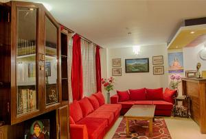 a living room with a red couch and a table at Hotel Le Primula in Gangtok