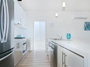 una cocina blanca con encimeras blancas y electrodomésticos de acero inoxidable en Seas the Day - Aldinga Beach - C21 SouthCoast Holidays en Aldinga Beach