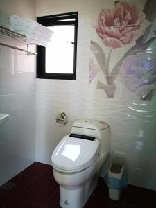 a bathroom with a toilet with a flower painting on the wall at 198紅帽民宿l市區l電梯l停車場 in Magong