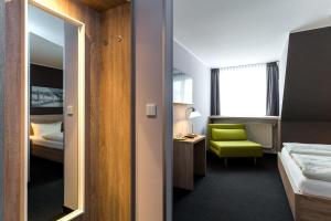 a hotel room with a green chair and a bedroom at Pension Alabama in Warnemünde